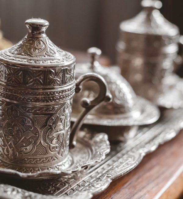 A closeup shot of an antique silver tea set with a blurry background